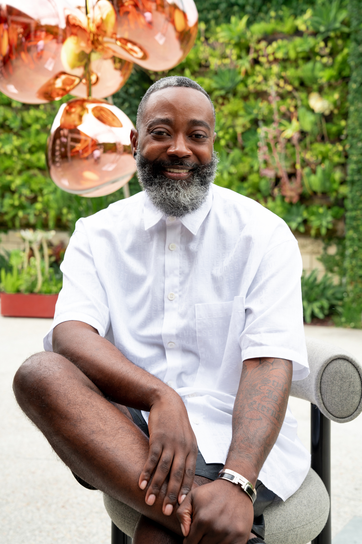 Man in white button up shirt against greenery backdrop