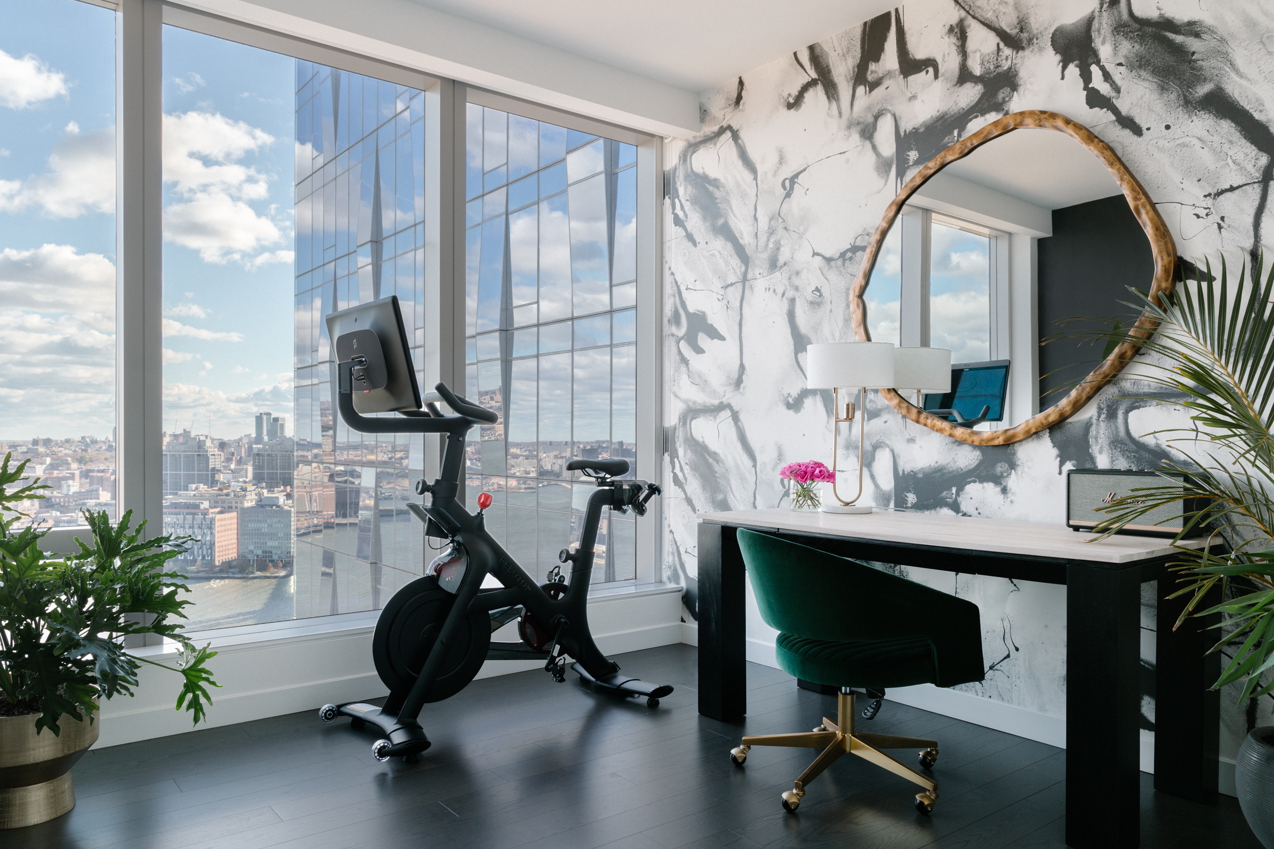 Office scene with at-home work out bike in corner, floor to ceiling windows looking out over the city