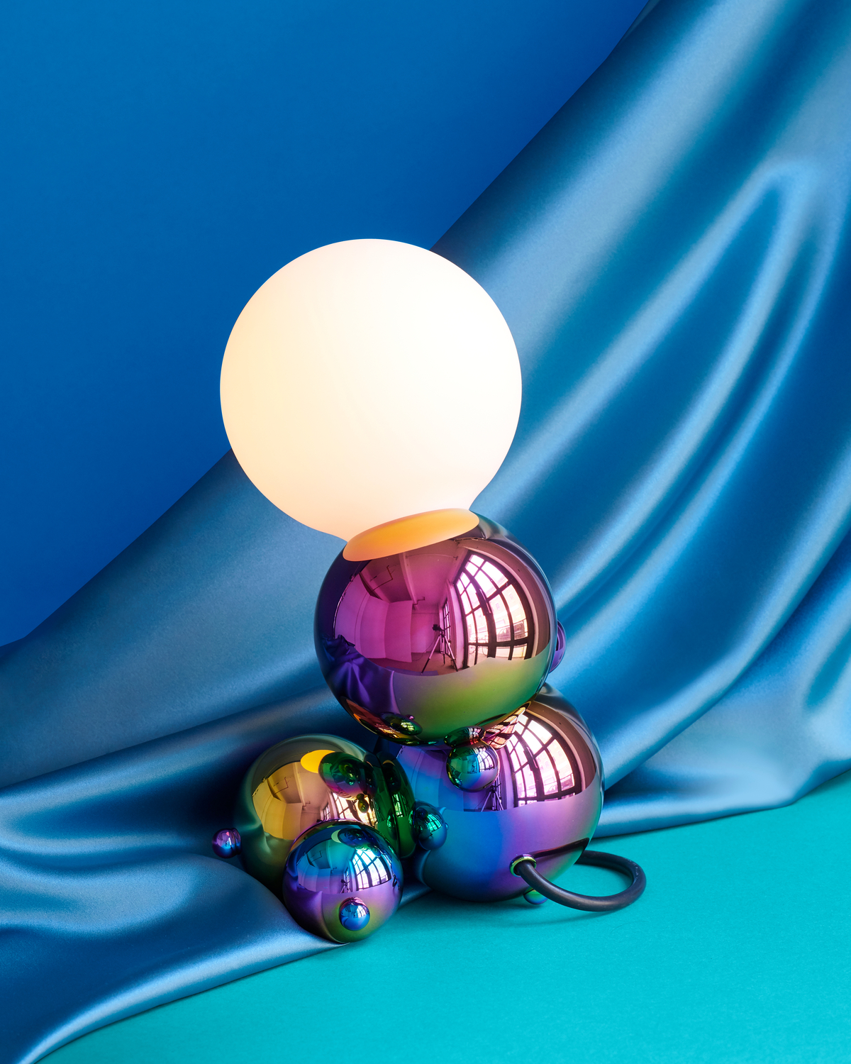 Rainbow colored spherical table lamp against a blue background