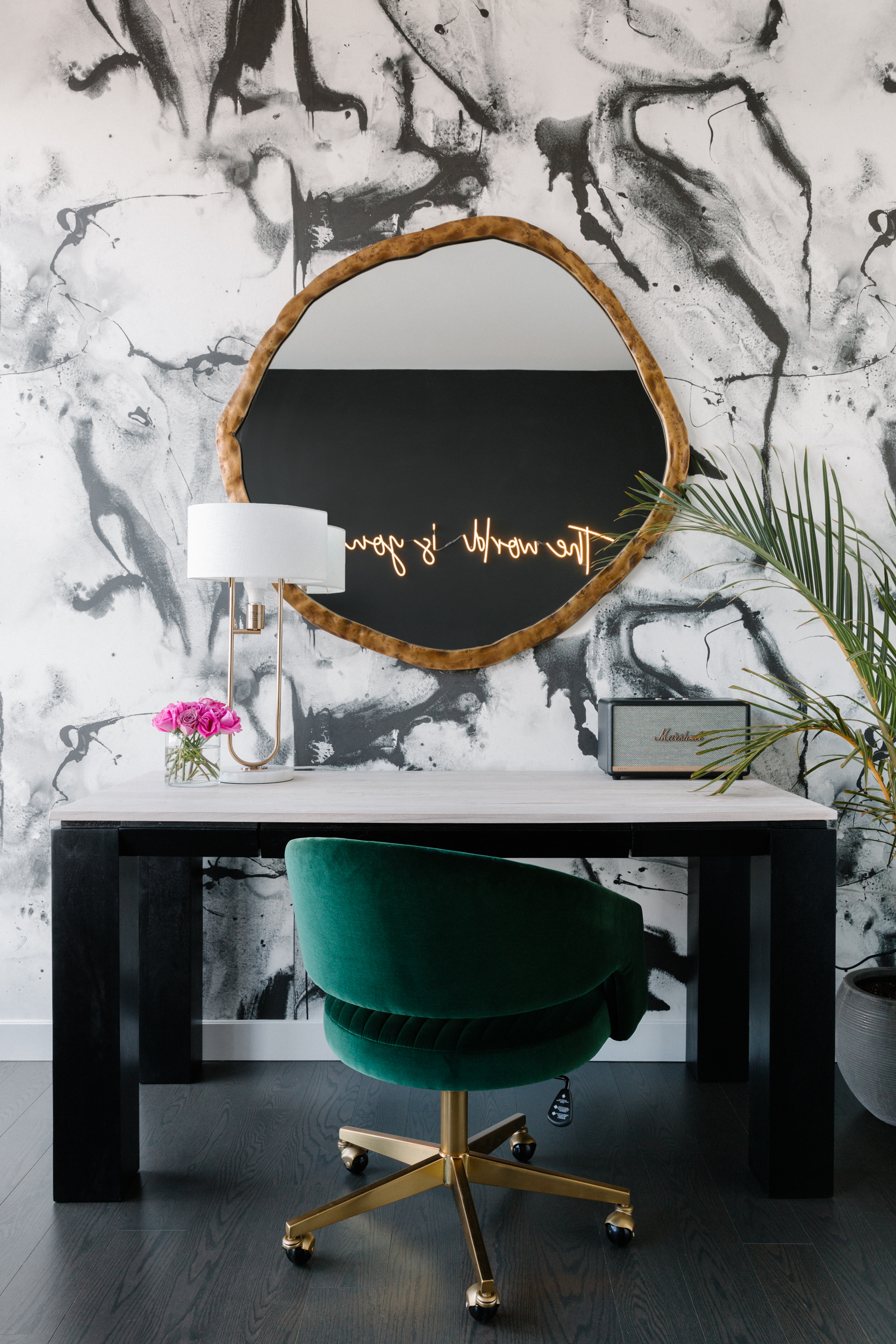 Desk with velvet green office chair against marble-styled wallpaper