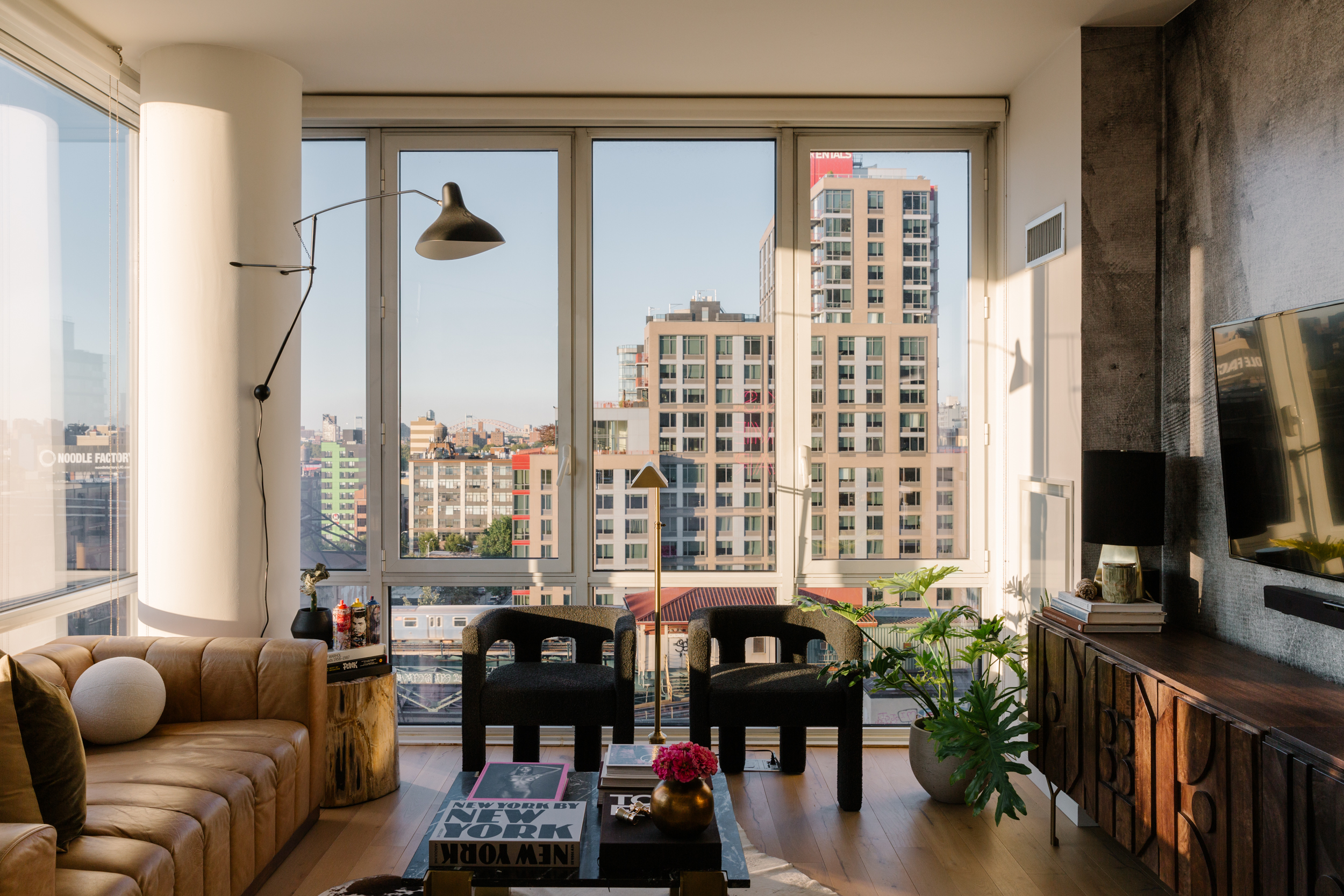Modern living room scene with cityscape behind floor to ceiling windows